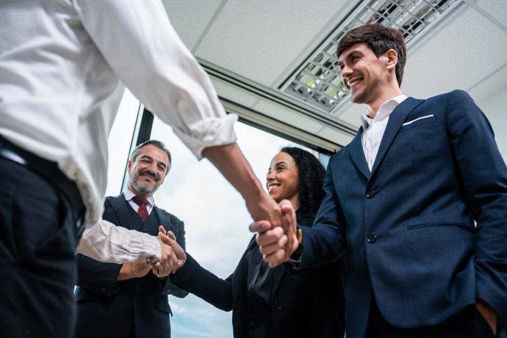 Business professionals shaking hands with clients after a meeting.